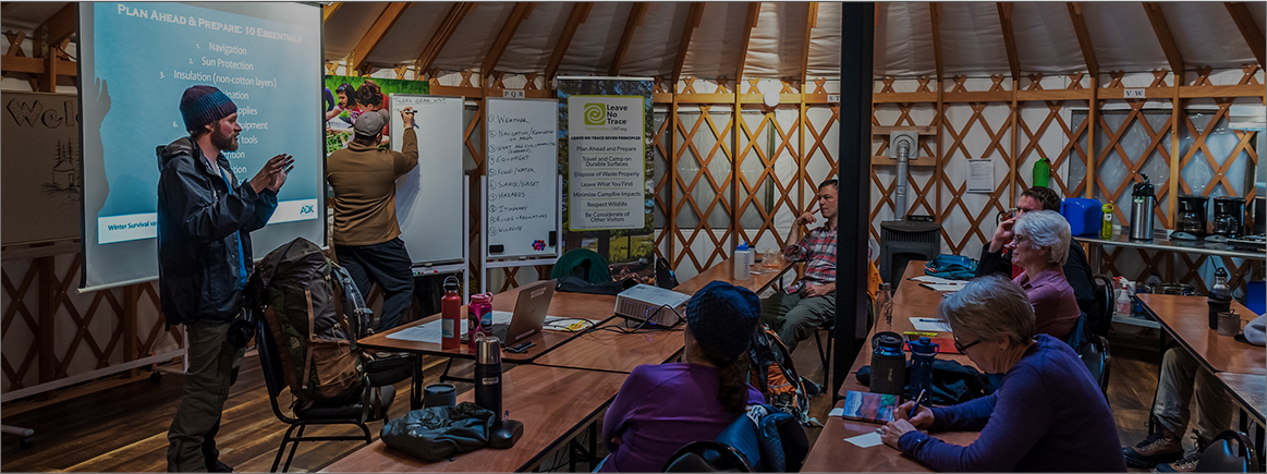 Tyler teaches a group of adults in a yurt
