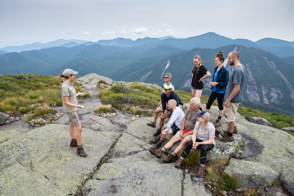 Kayla talks to a group of hikers on a summit