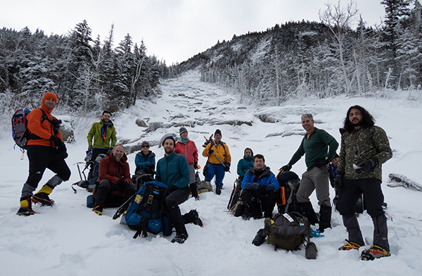A group of people resting at the base of an icy rock slide