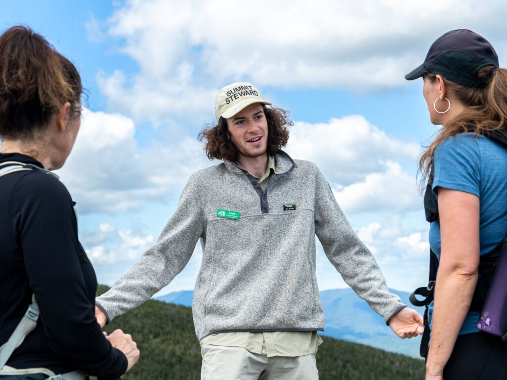 A man speaking to two hikers.