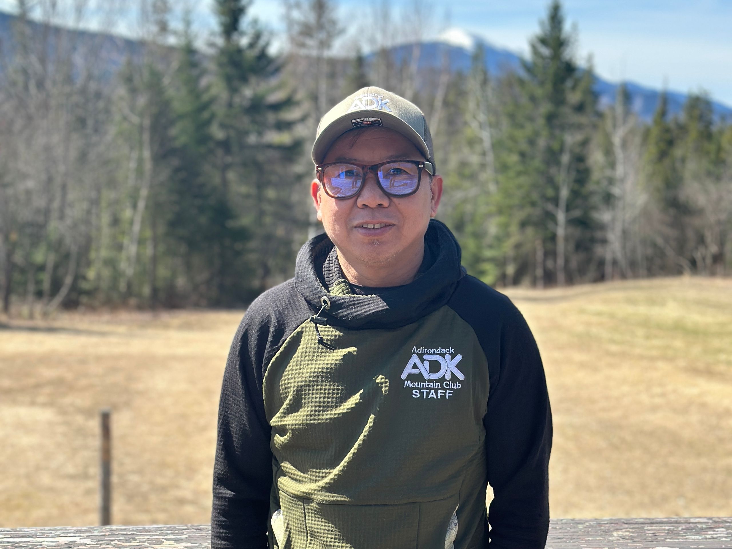 man wearing hat and glasses with a mountain in the background