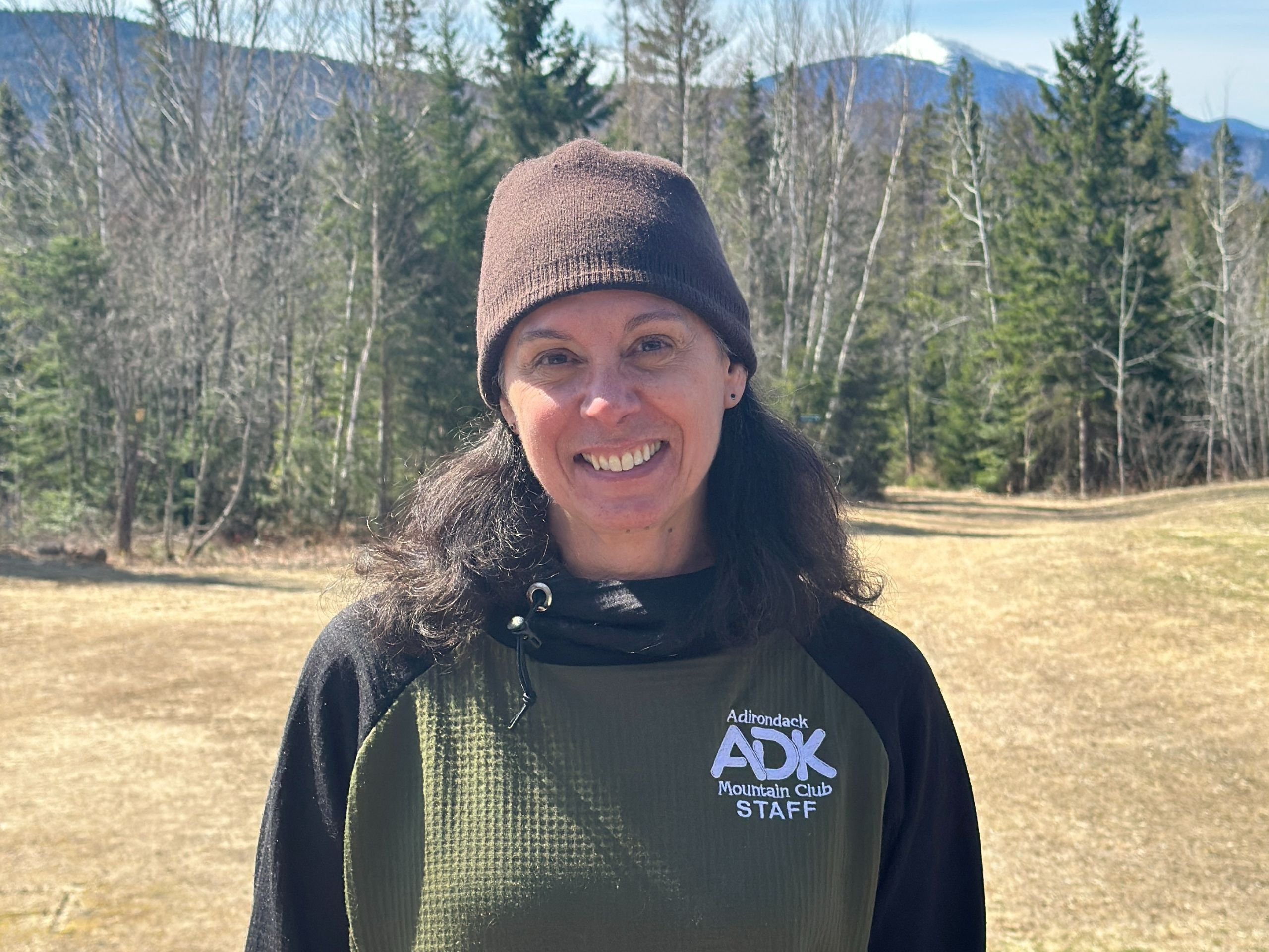 a woman wearing a hat with a mountain in the background