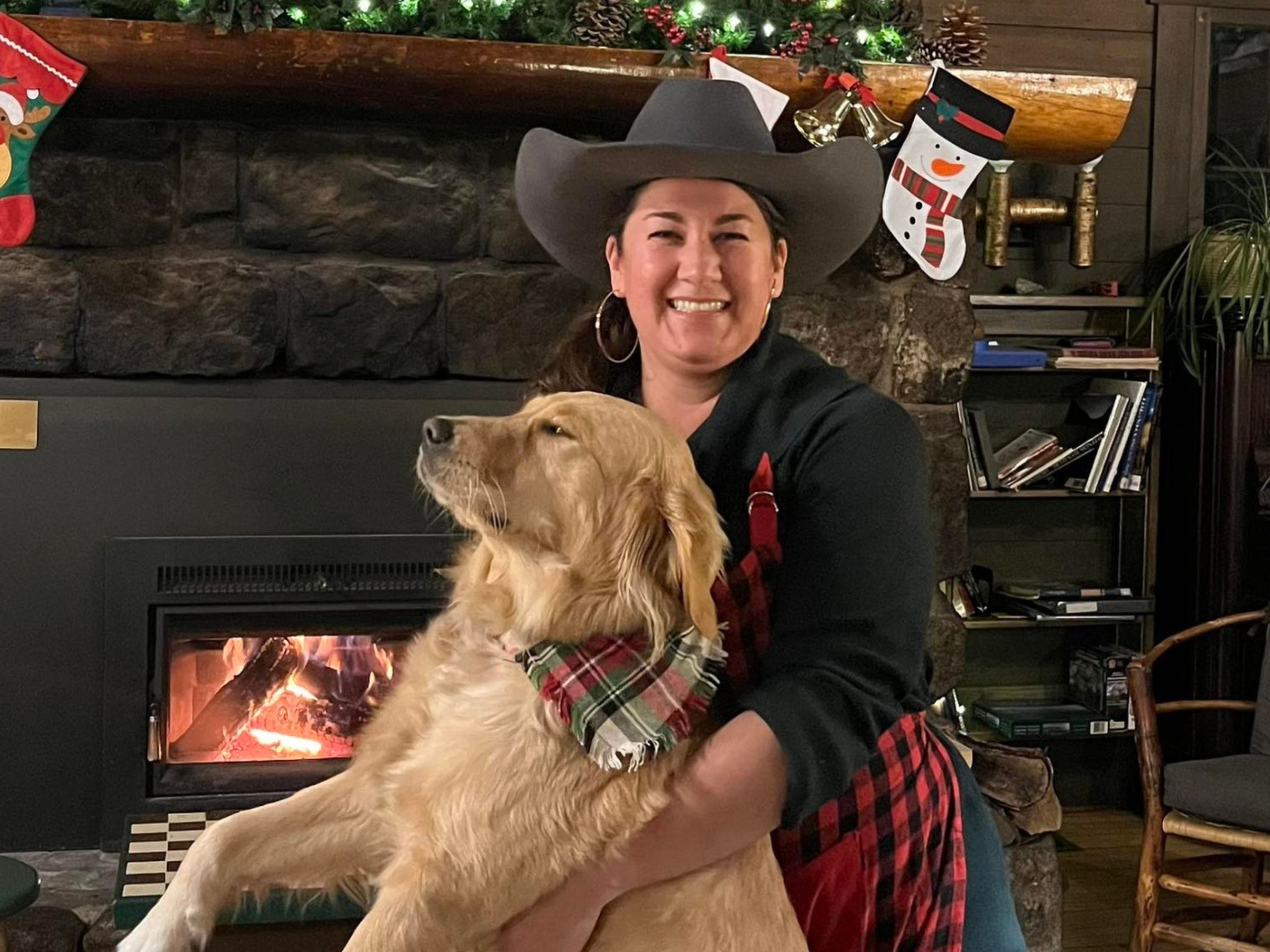 woman wearing a cowboy hat holds a dog
