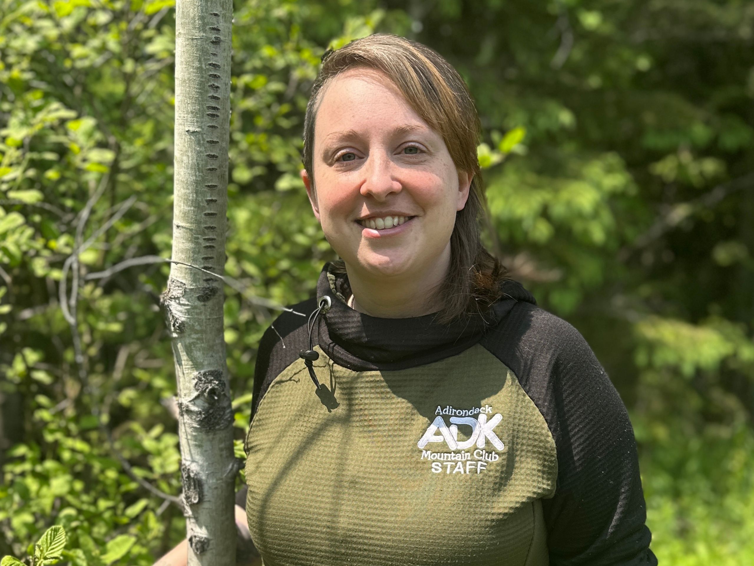 portrait of a woman outdoors standing next to a tree