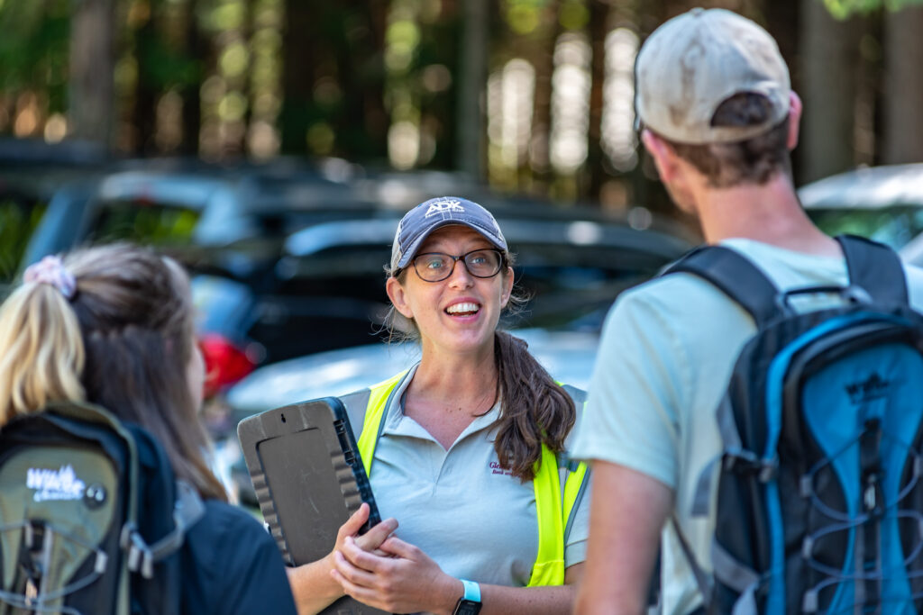 female volunteer trailhead steward speaks to hikers at a trailhead