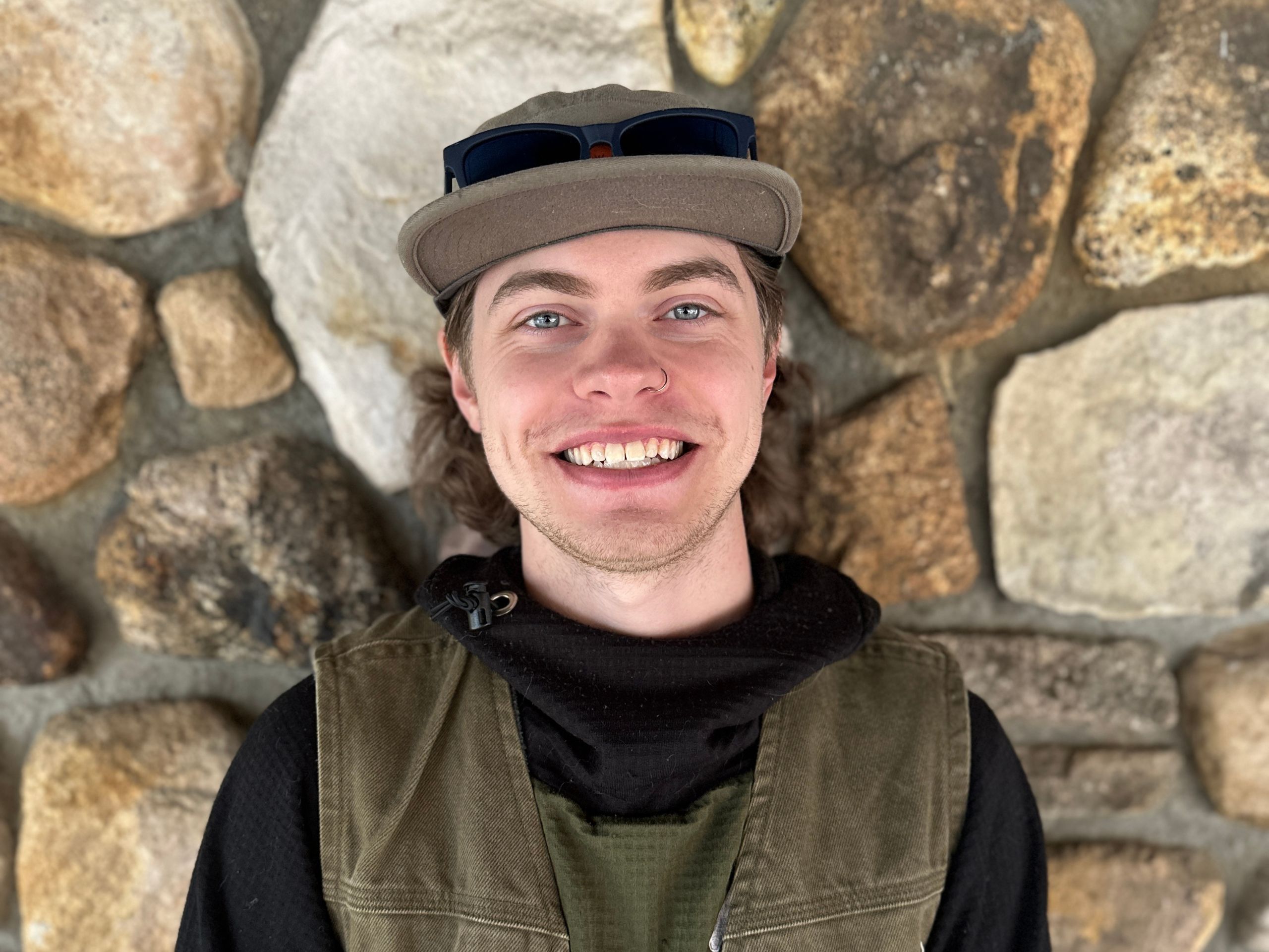 a portrait of a man smiling in front of rocky wall