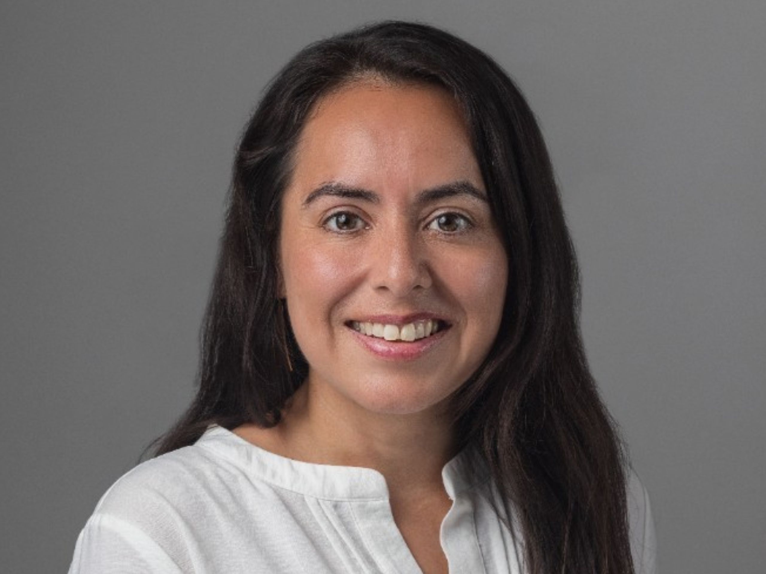 headshot of a dark haired woman on a gray background