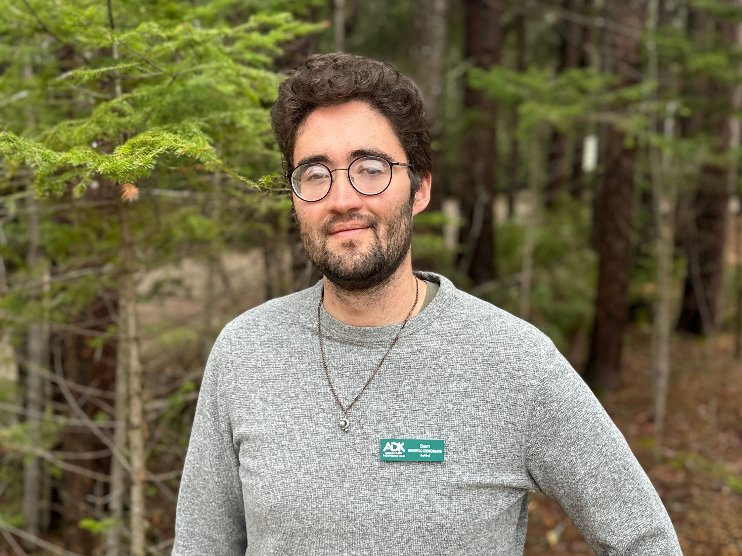 photo of a man wearing glasses and a gray t-shirt in the woods