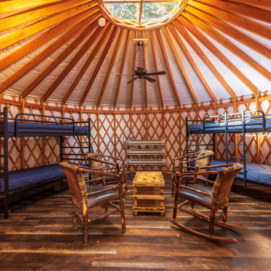 the inside of a camping yurt with four rocking chairs and two bunk beds