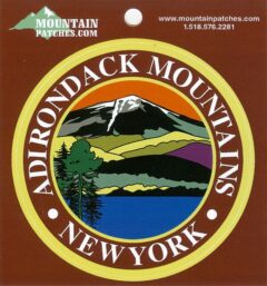 Circular badge logo for Adirondack Mountains, New York, featuring a mountain landscape inside a gold ring and the text 'ADIRONDACK MOUNTAINS NEW YORK' around the edge; includes a lake scene and green trees in the center, with website text at the top.