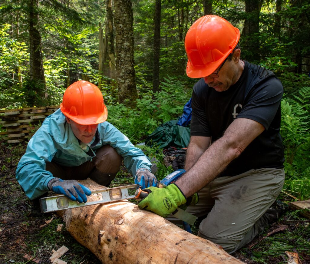 national trails day volunteers check the level of a chopped log for a bridge