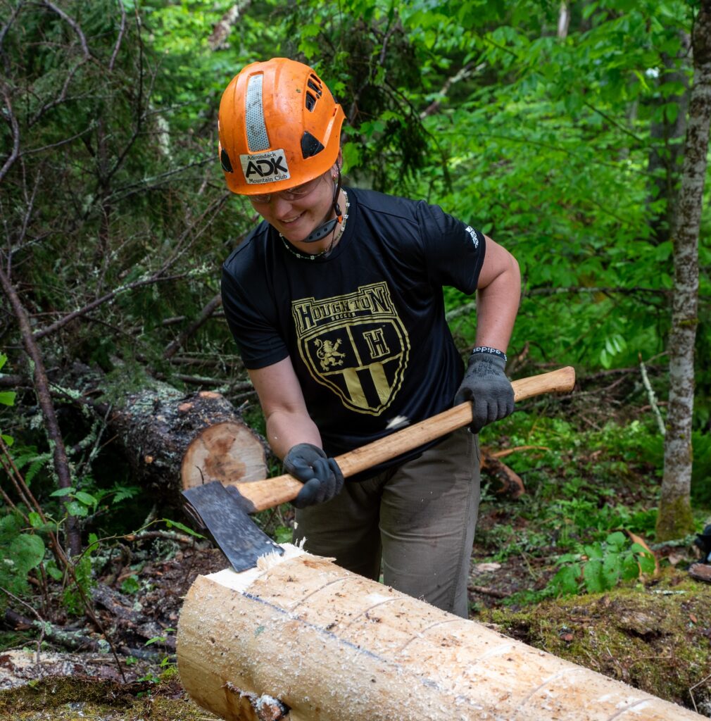 trail worker holding an axe and wearing a bright orange protective hard hat