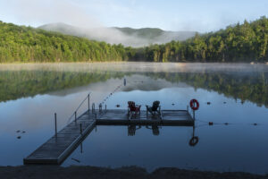 A view of the dock with adirondack chairs on heart lake during the early morning