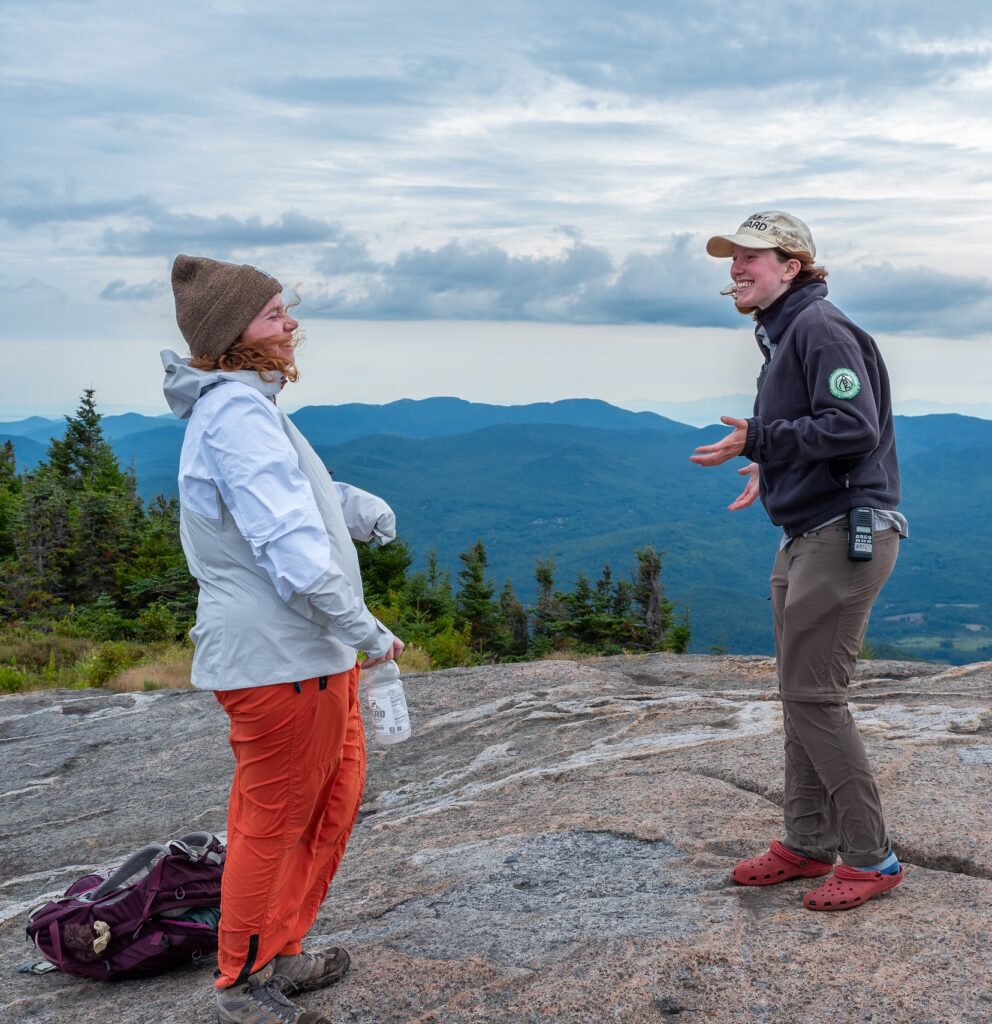 summit steward speaks to a hiker on a cloudy day in the adirondacks