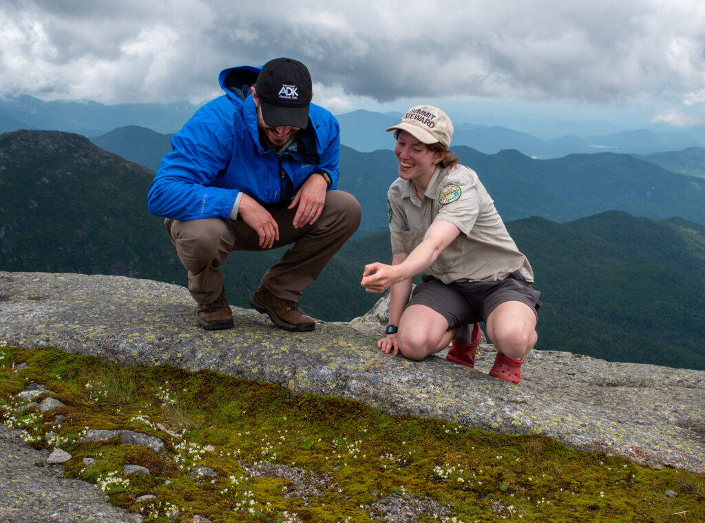 a summit steward speaks to a hiker on a mountain summit