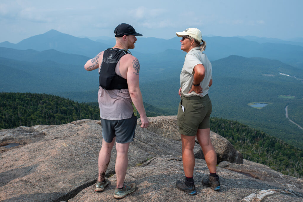 volunteer summit steward speaks to hiker on marcy