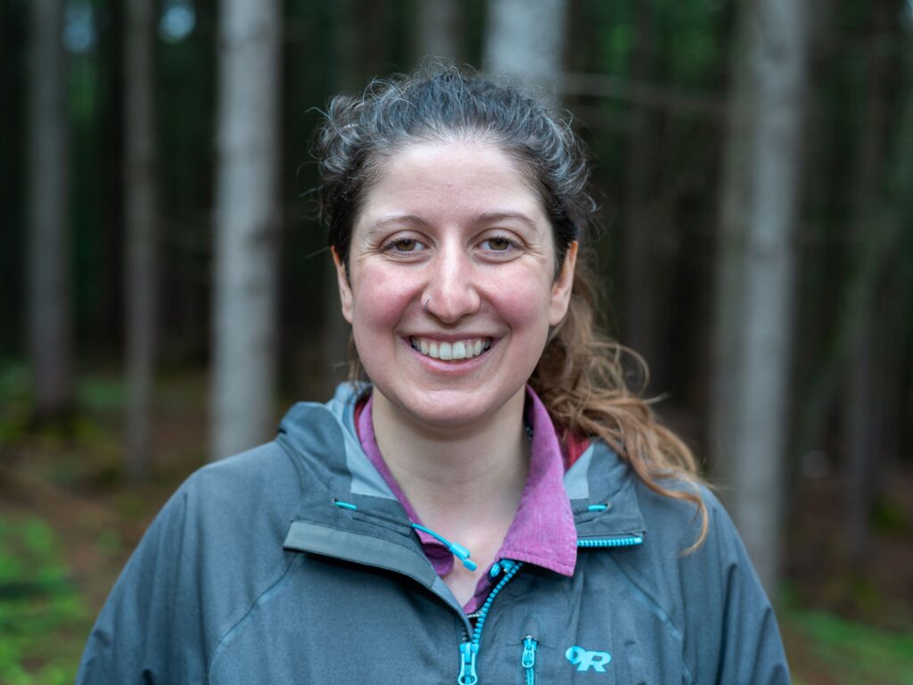 woman stands in front of woods