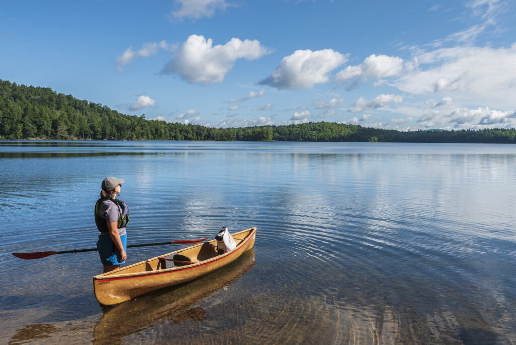 Canoe on little clear with paddler standing next to canoe