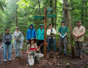 volunteer trail crew poses in front of new junction signs