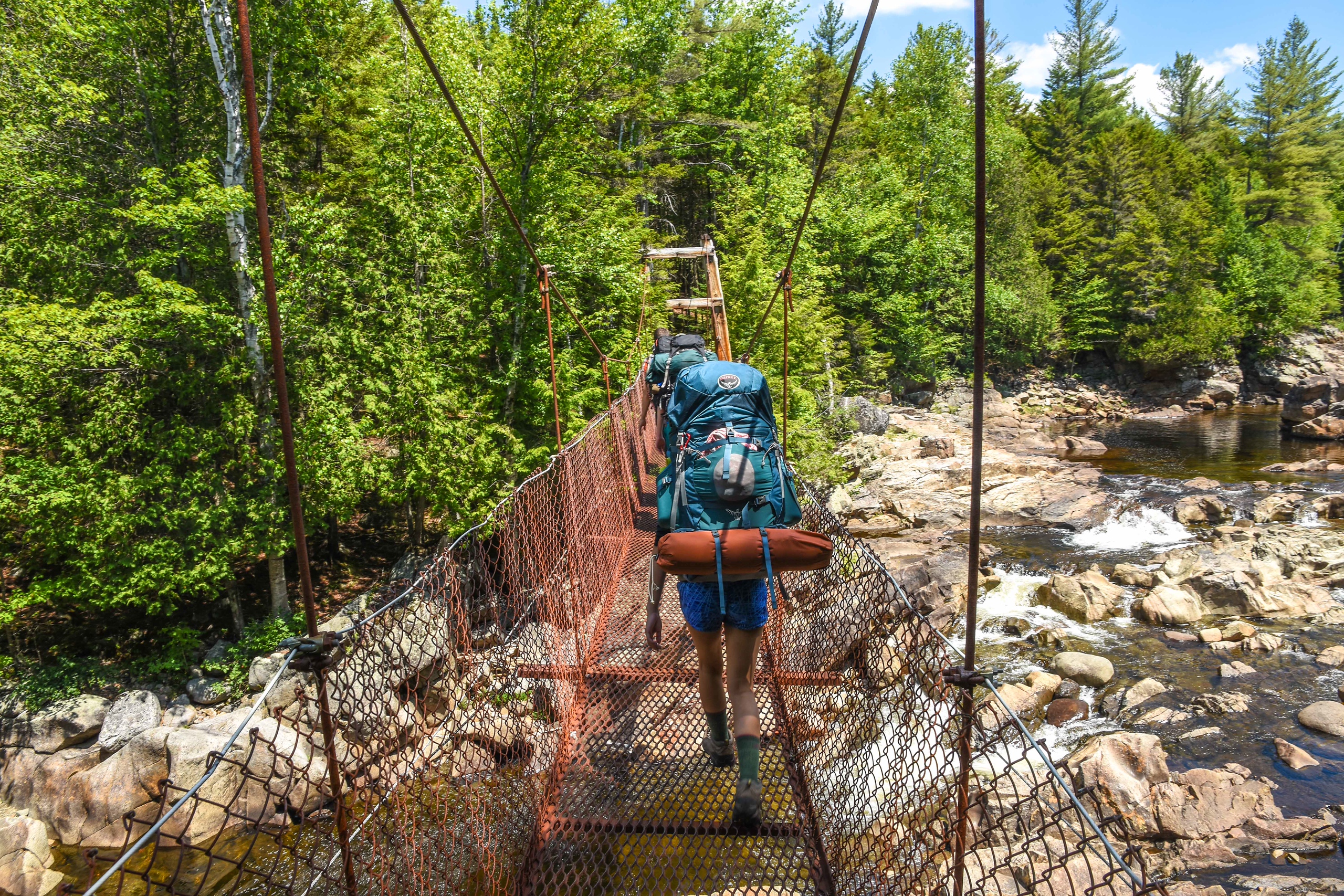 hiker crosses a bridge on a backpacking trip