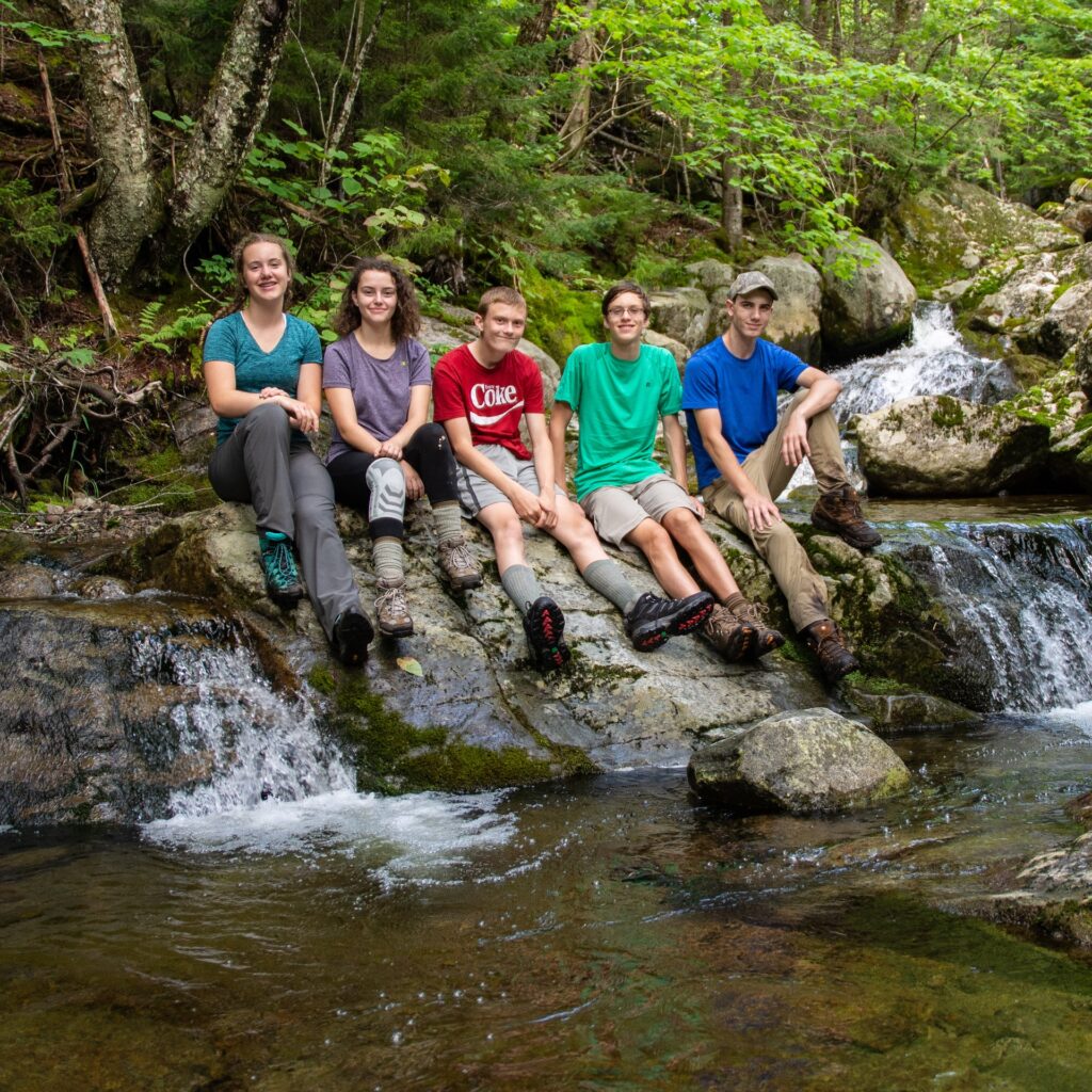 teens sitting by a river in the adirondacks