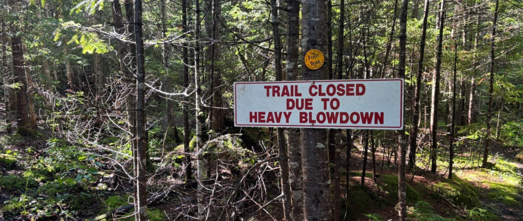 a sign that reads "trail closed due to heavy blowdown"