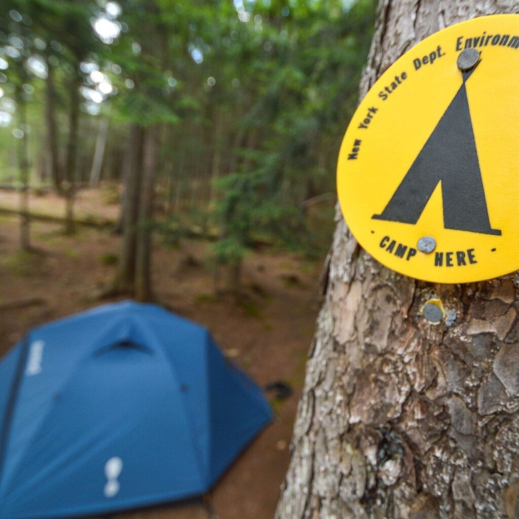 camp here marker and campsite with blue tent set up