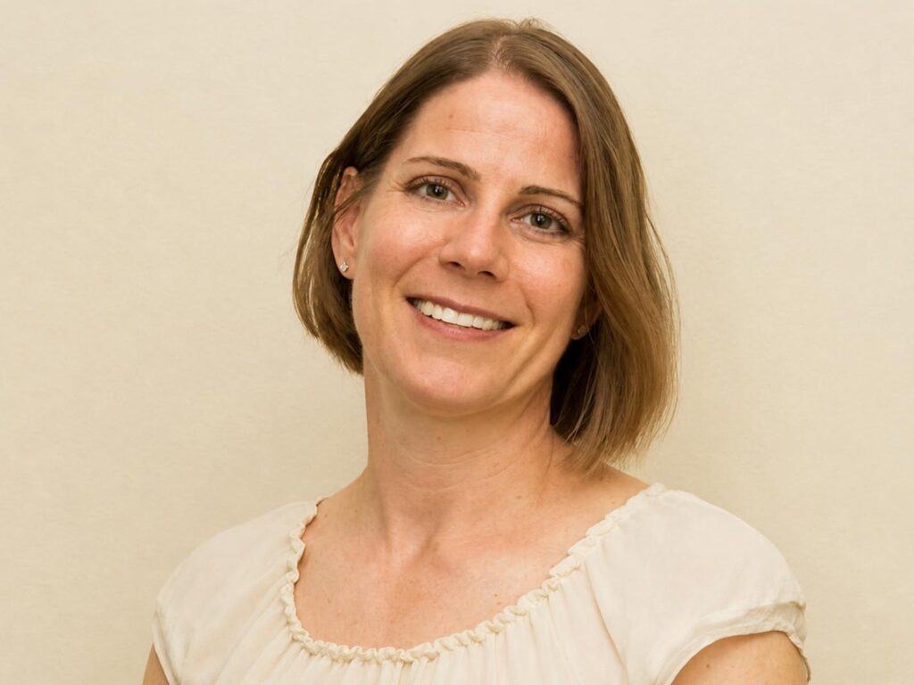 headshot of woman against a tan background