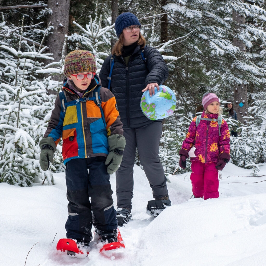 two homeschool students and a teacher walk through the snow in the adirondacks