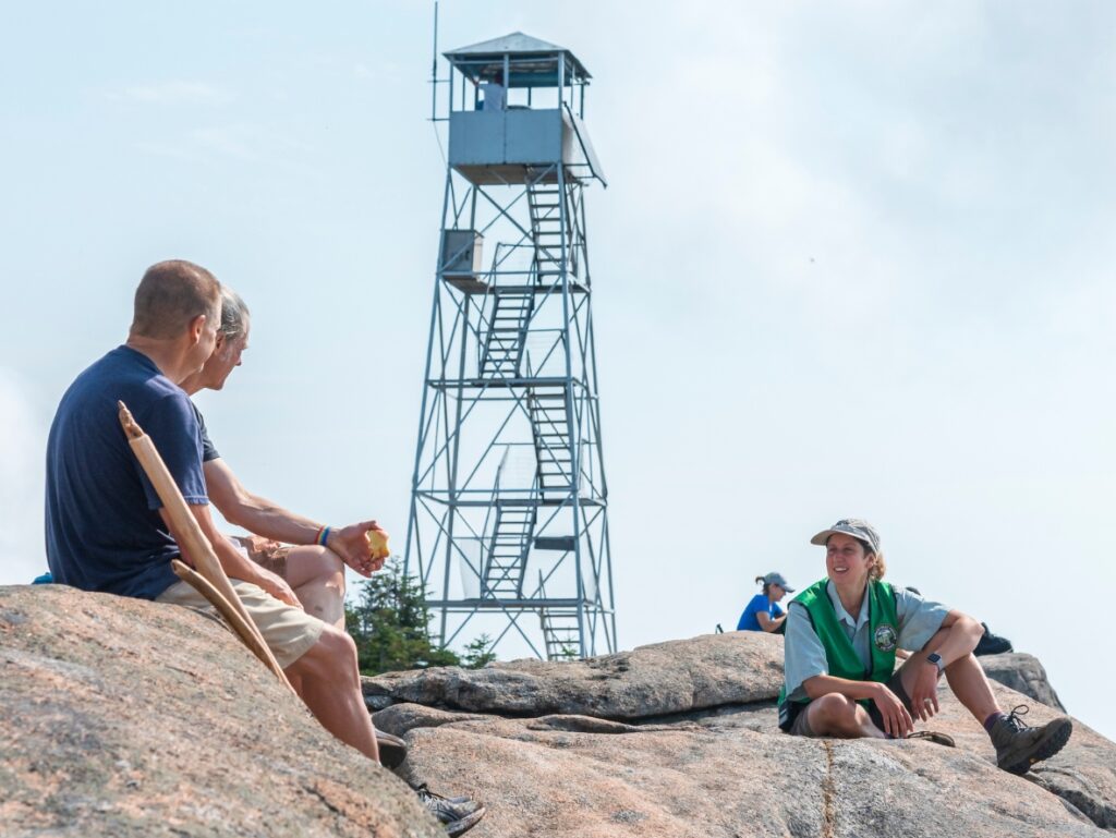 a fire tower steward speaks to a hiker on hurricane mountain