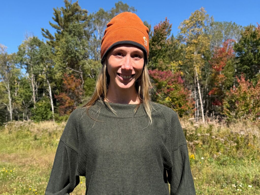 a portrait of a woman with blonde hair wearing an orange hat and green shirt