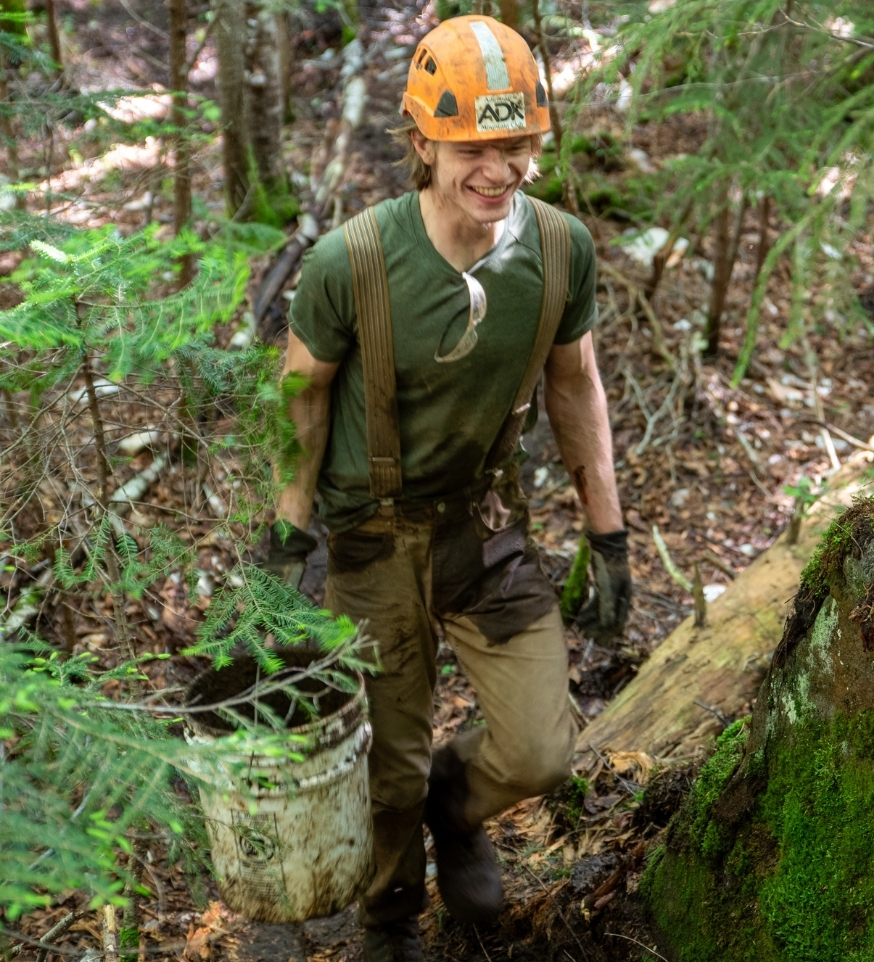 trail crew worker wearing a hard hat and carrying a bucket