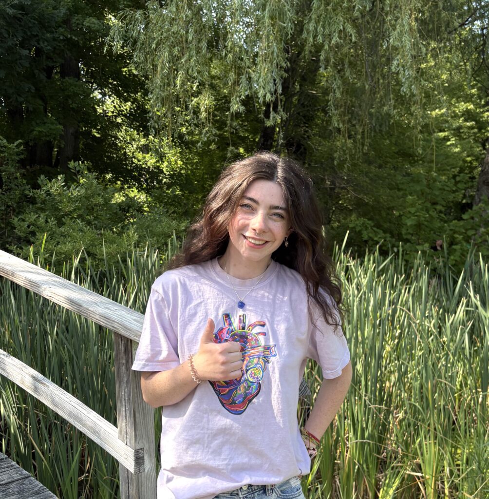 portrait of woman in the woods doing a thumbs up gesture with her right hand