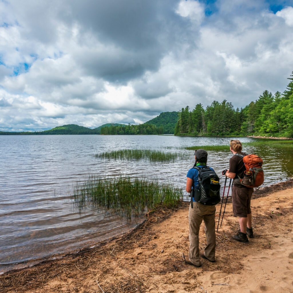 two hikers look out over lake Lila in the adirondacks