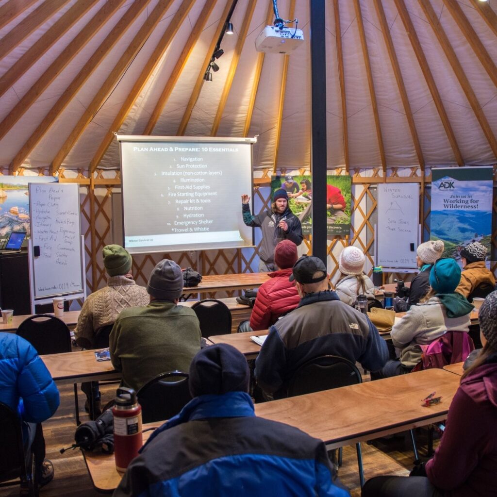 man delivers presentation to a group of students in a yurt