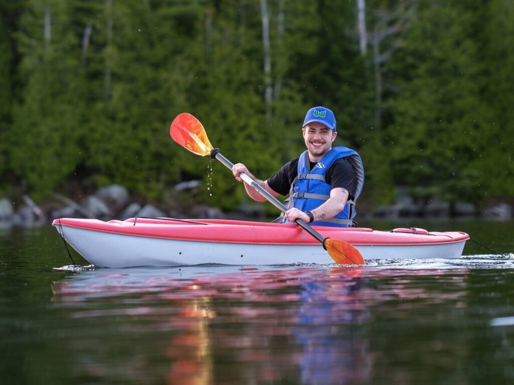 person paddling a red and white kayak