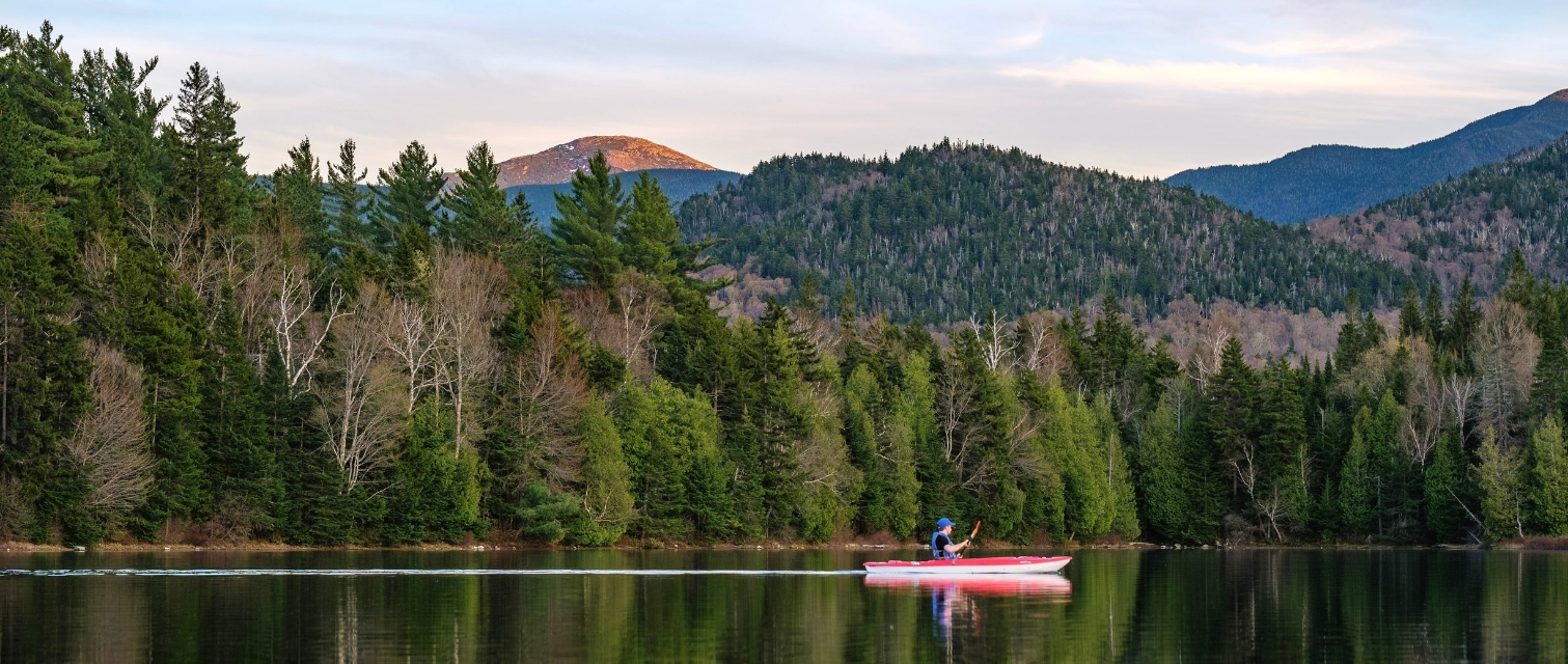 a solo kayaker paddles on Heart Lake in the Adirondacks