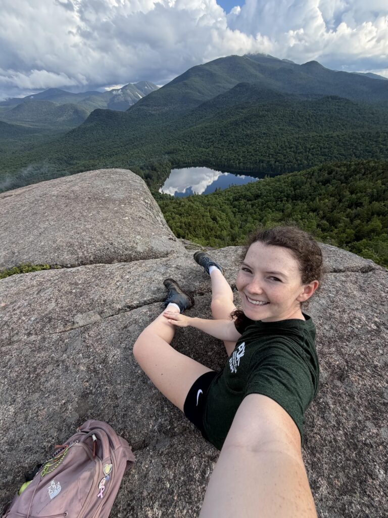 a woman taking a selfie at the summit of mount jo with heart lake in the background