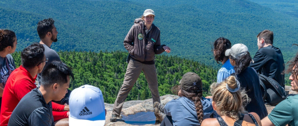 summit steward speaks to large group of hikers