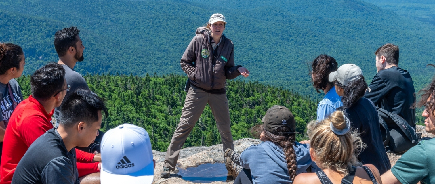 summit steward speaks to large group of hikers