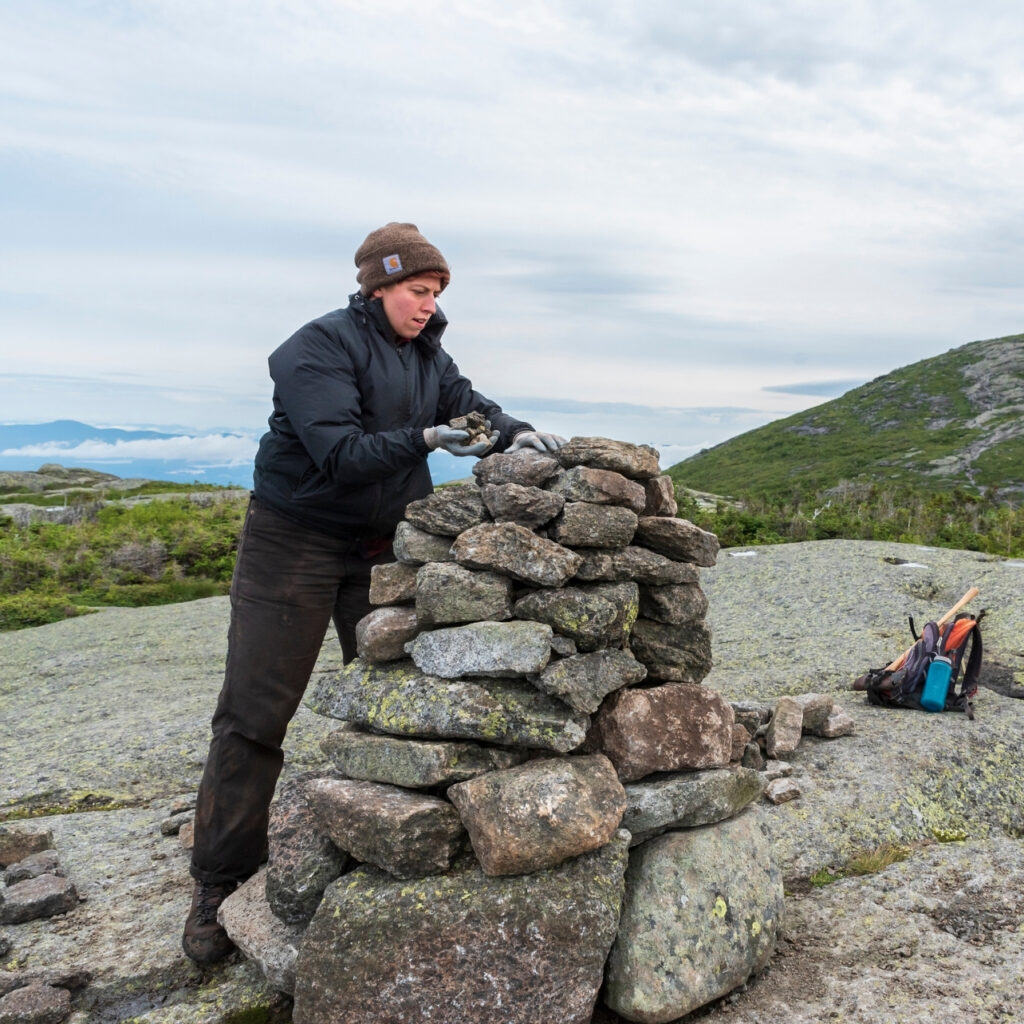 summit steward builds a cairn