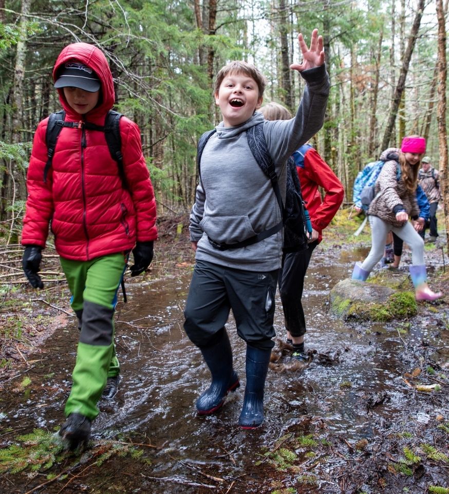 students walk through mud during spring hike at three seasons at heart lake