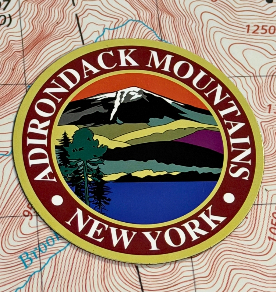 circle magnet that reads Adirondack Mountains New York lying on a map table