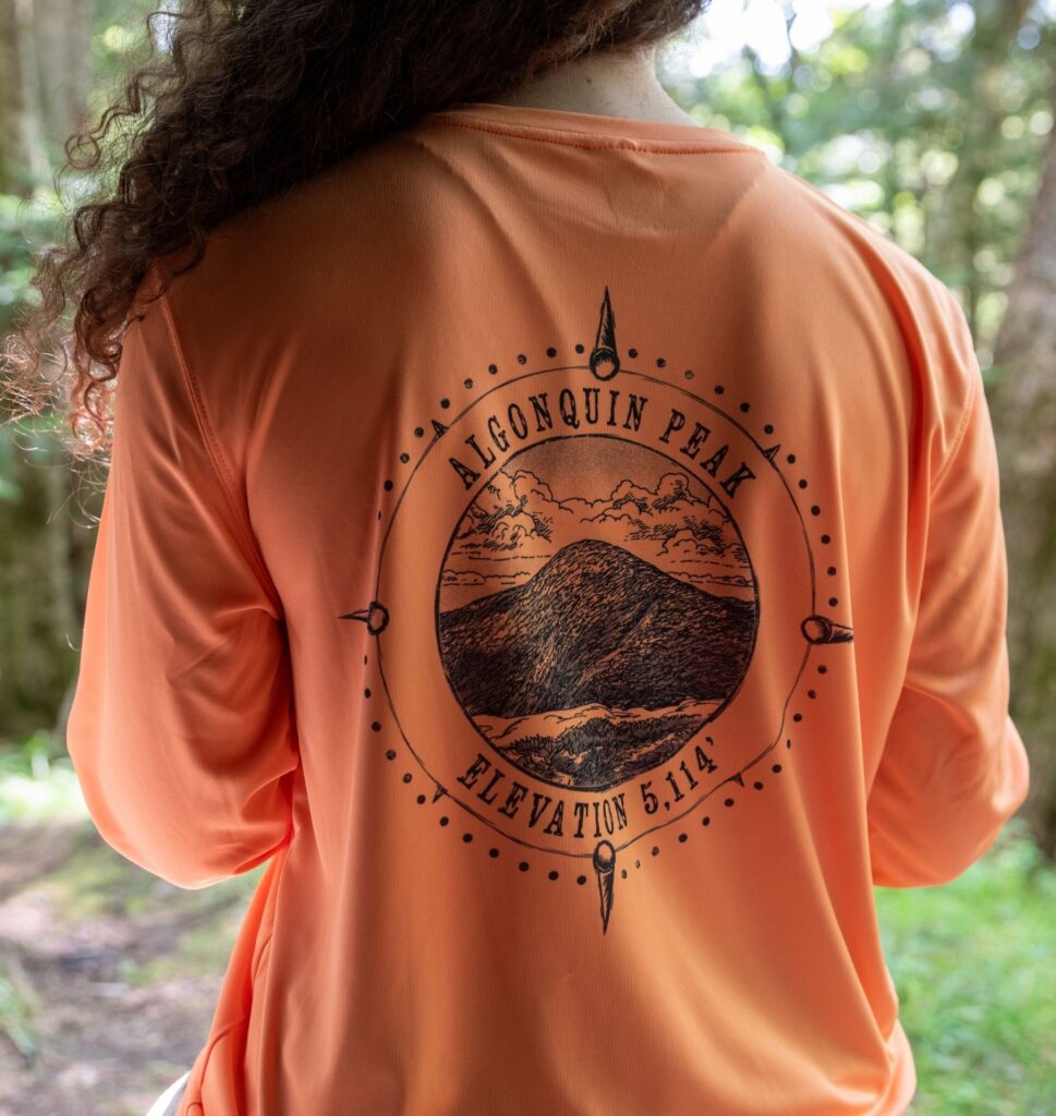 woman with long brown hair wearing Algonquin Peak tech shirt