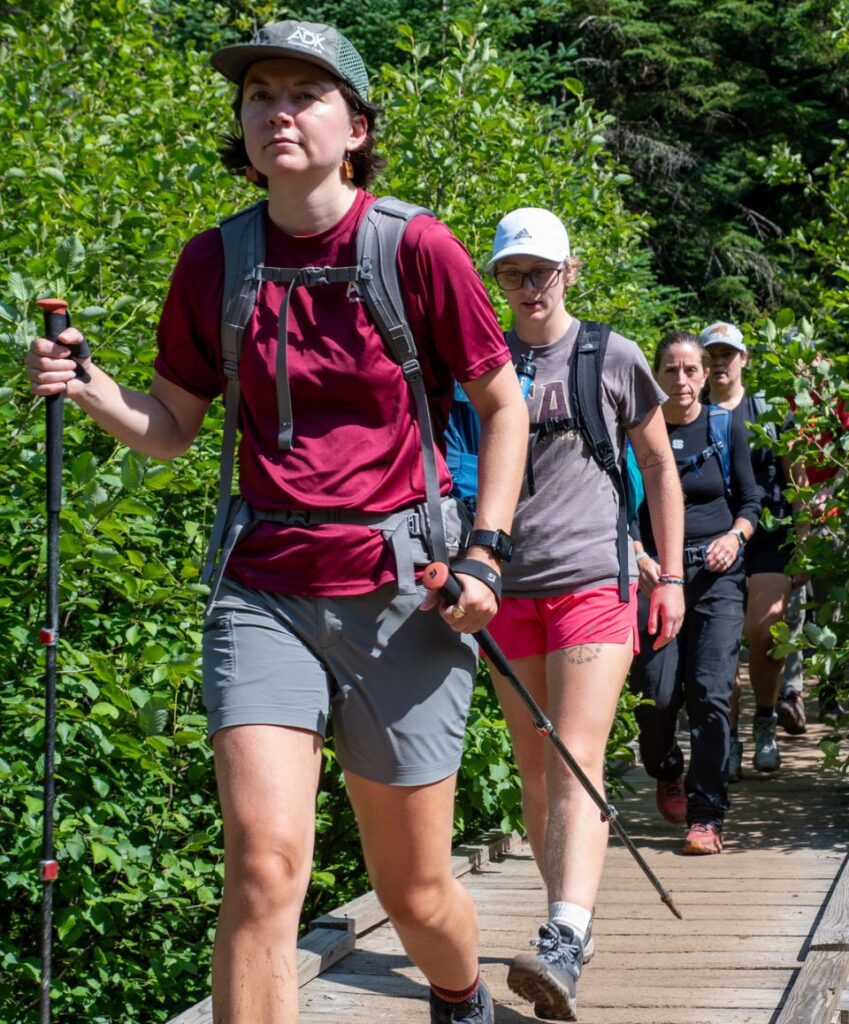 group of hikers crosses van hoevenberg trail on bridge