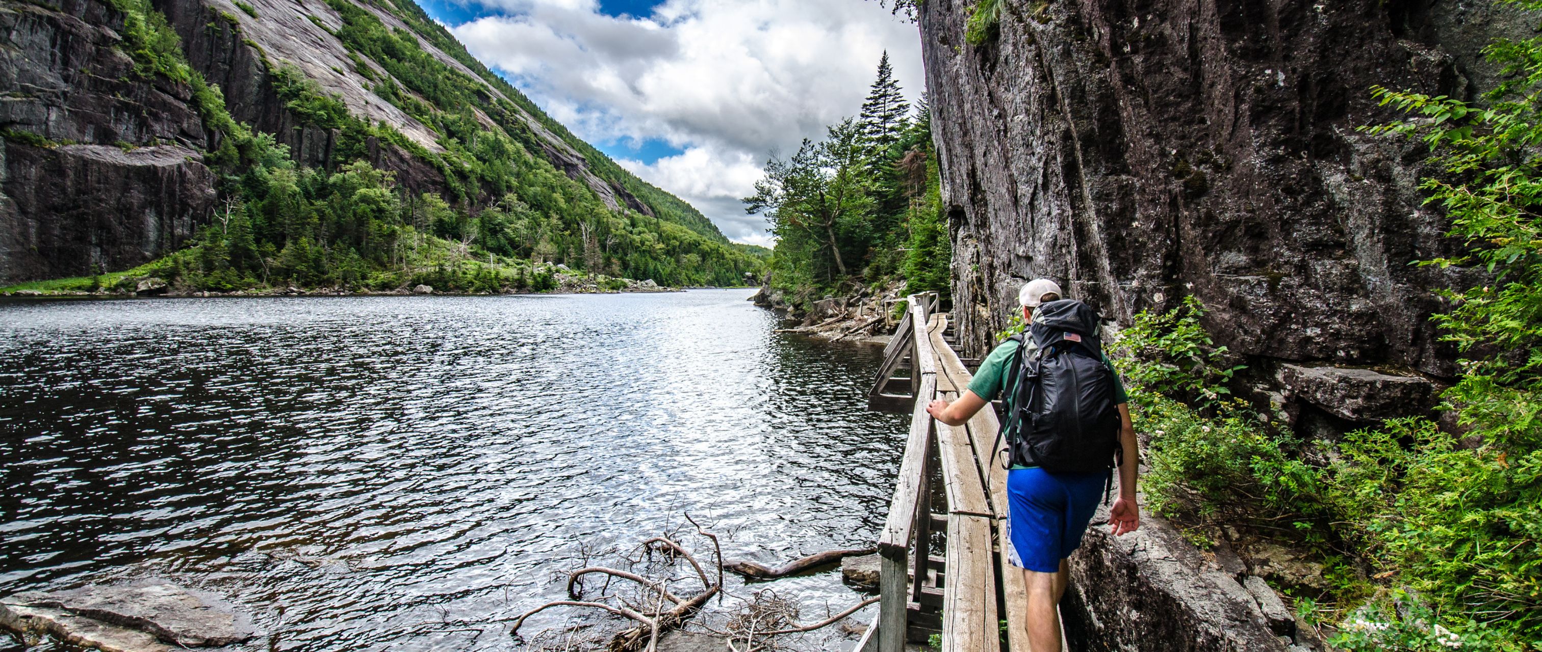 hiker walks along hitch-up Matilda along Avalanche Lake