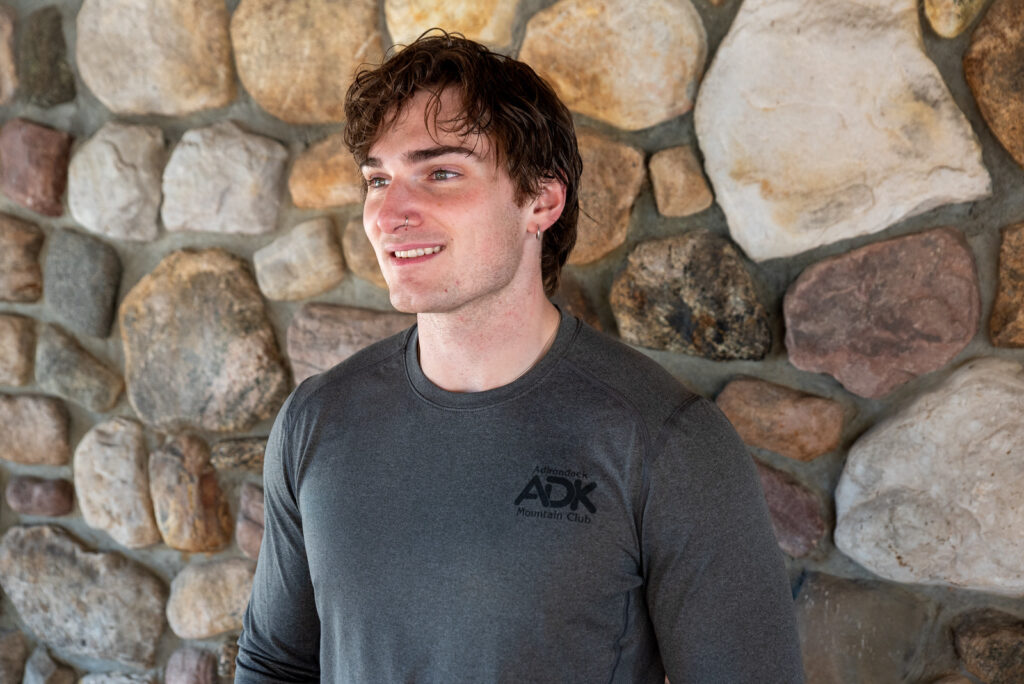 person modeling a long-sleeve gray shirt again a rock chimney background