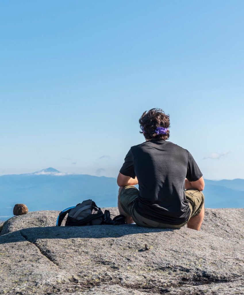 lone hiker sits at summit of algonquin