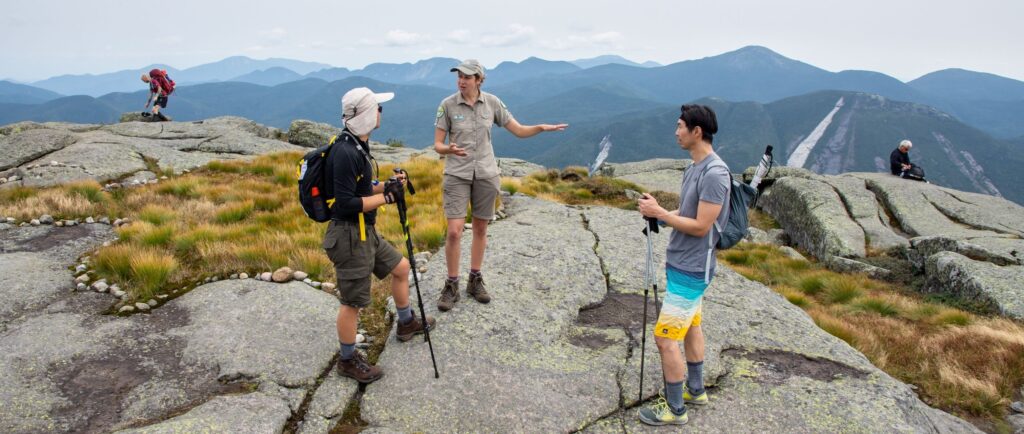 summit steward speaks to two hikers on algonquin