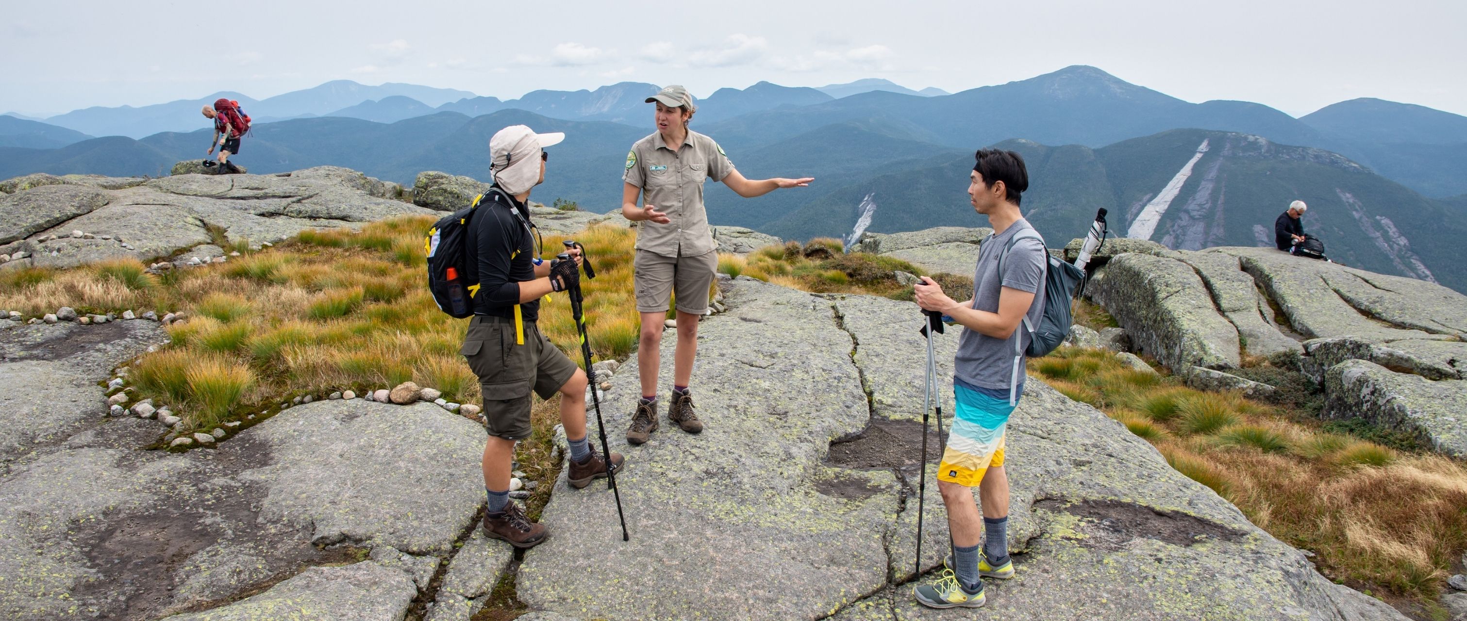 summit steward speaks to two hikers on algonquin